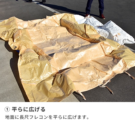 ①平らに広げる　地面に長尺フレコンを平らに広げます。